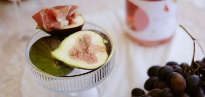 A luxurious still life featuring figs, prosciutto, red grapes, and wine.
