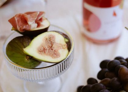 A luxurious still life featuring figs, prosciutto, red grapes, and wine.